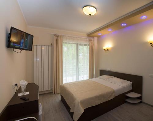 伯伊莱海尔库拉内Hotel Holiday Maria的卧室配有一张床,墙上配有电视。