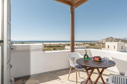 米科利维亚Zanneta Apartments & Suites的阳台配有桌椅,享有海景。