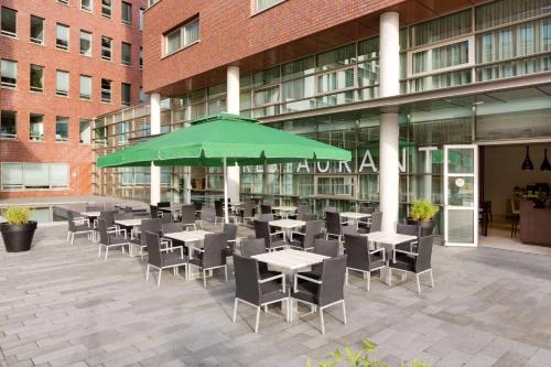 阿默斯福特阿默斯福特NH酒店的一间设有桌椅和绿色遮阳伞的自助餐厅