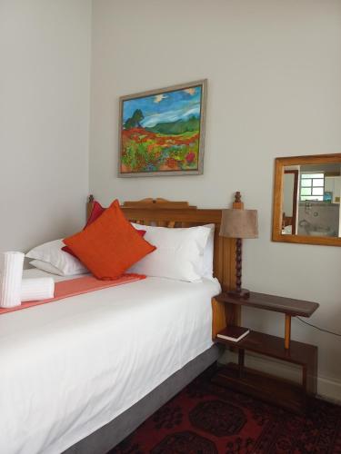 威廉王城Dreamers Guesthouse - NO LOADSHEDDING的一间卧室配有带白色床单和橙色枕头的床。