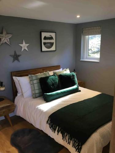 LonghopeCute studio cottage. Wood burner. Amazing views的卧室配有一张带绿色枕头的床,墙上挂着星星。