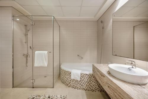 迪拜Oaks Liwa Heights Hotel Suites的带浴缸、水槽和淋浴的浴室