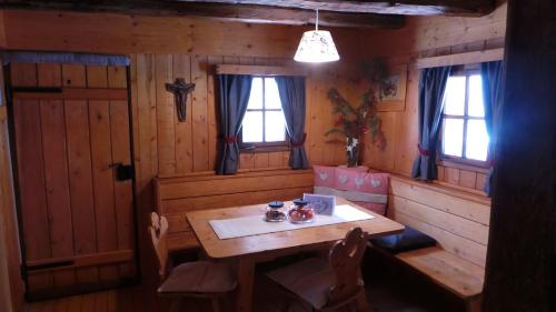 安泰塞尔瓦·迪·梅佐木屋维尔德高度假屋的一间带木桌和2扇窗户的用餐室