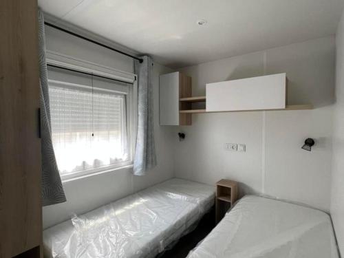 圣让-德蒙Superbe Mobil home 6-8 personnes (57)的一间小卧室,配有两张床和窗户
