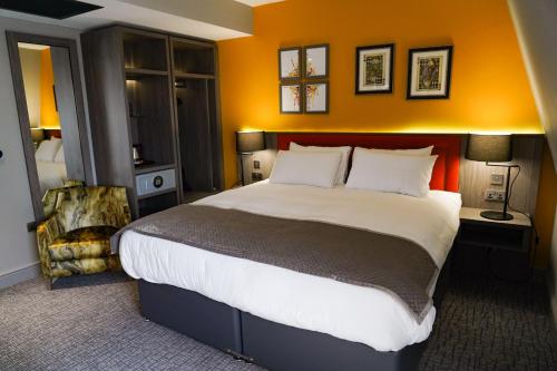 泰恩河畔纽卡斯尔Great North Hotel的一间卧室配有一张带橙色墙壁的大床