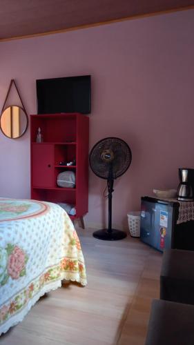 卢米亚Chalés Mimar Lumiar Suítes individuais的一间卧室配有一张床和一台平面电视