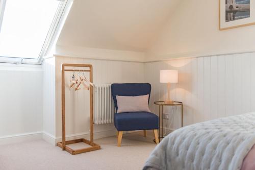 布罗德斯泰Liberty Cottage的一间卧室配有蓝色椅子和镜子