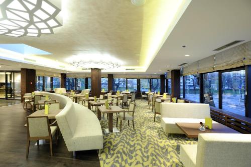 萨拉热窝萨拉热窝布里斯托尔诺富特酒店的餐厅设有白色的椅子和桌子以及窗户。