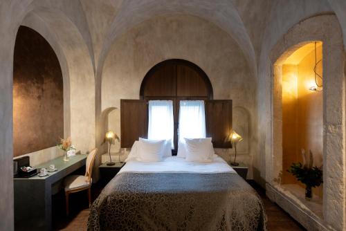 科尔多瓦Hospes Palacio del Bailio, a Member of Design Hotels的一间卧室配有一张床、一张桌子和一个窗户。