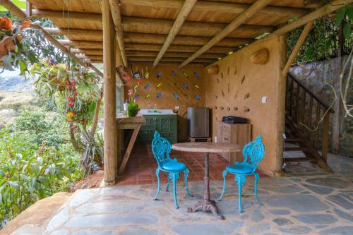 卡利San Andrés, Hermosa Cabaña Privada en Reserva Natural - Cali Valle del Cauca的天井配有桌子和2把蓝色椅子