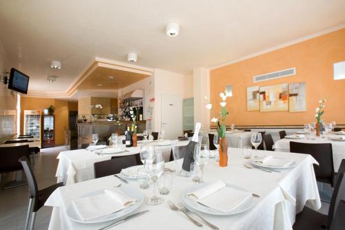 托莱港Hotel Ristorante Klaus的用餐室配有白色桌子和黑色椅子
