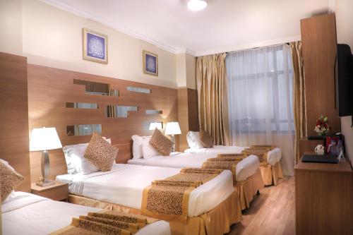 麦地那Deyar Al Eiman Hotel的酒店客房设有四张床和窗户。