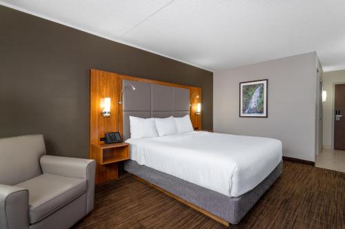 圣约翰堡Ramada by Wyndham Northern Grand Hotel & Conference Centre的配有一张床和一把椅子的酒店客房