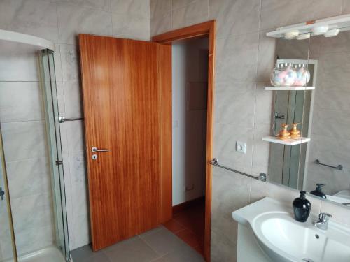 CalhetaCasa da Eira的带淋浴和盥洗盆的浴室以及木门。