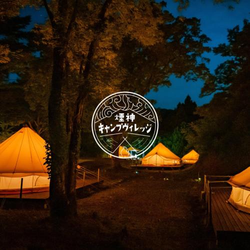 丰冈市煙神キャンプヴィレッジ的一群帐篷在晚上有标志