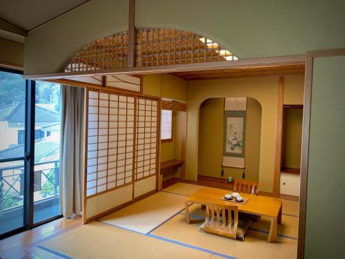 武雄市unsui 武雄蓬莱町 雲水的客房设有桌子和大窗户。