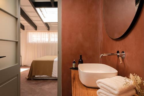 马翁El Consul Mao - Hotel Boutique的一间带水槽的浴室和一间带床的房间