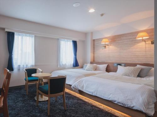 宫古岛Miyako Daiichi Hotel的酒店客房带两张床和一张桌子以及椅子。