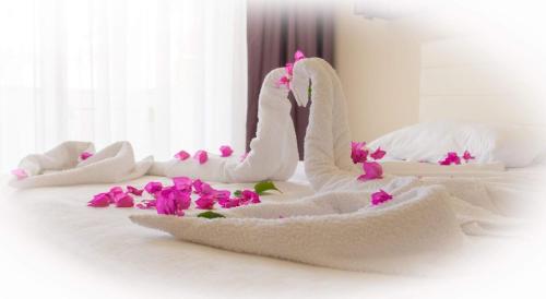凯麦尔Agva Apart Otel的白色毛巾天鹅坐在鲜花盛开的床上