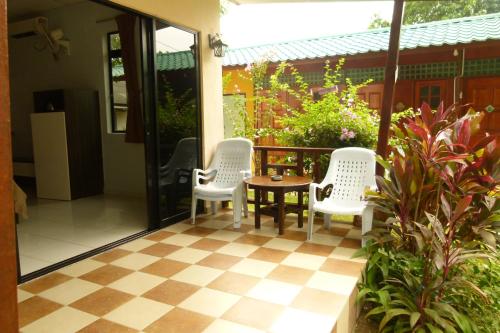 Kampung TekekCheers Garden Chalet的门廊上设有带三把椅子和一张桌子的庭院