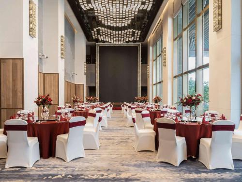 海口海口索菲特酒店的宴会厅配有桌子、白色椅子和屏幕