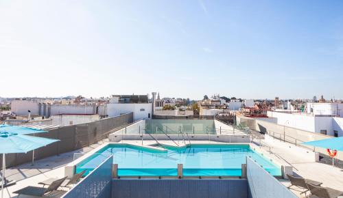 塞维利亚Hotel Macià Sevilla Kubb的一座带遮阳伞的建筑的顶部游泳池