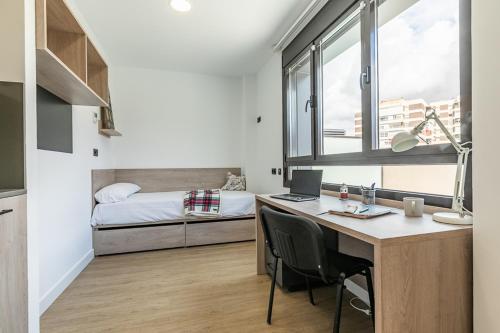 马德里micampus Madrid Sinesio Delgado Student Residence的一间卧室配有书桌和一张带笔记本电脑的床。