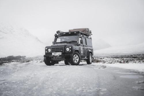 莫珀斯Land Rover Defender Luxury Camper的吉普车沿着雪覆盖的道路行驶