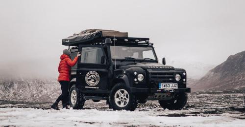 莫珀斯Land Rover Defender Luxury Camper的站在雪地里一辆黑色吉普车旁的人