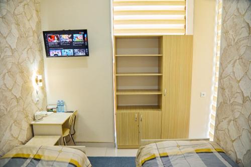 撒马尔罕YUKSALISH HOSTEL的客房设有两张床、一张桌子和一台电视机。