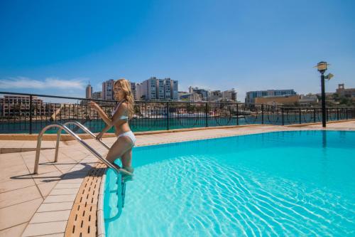 圣朱利安斯马耳他科林西亚海滩海滨度假酒店的站在游泳池自行车上的比基尼女人