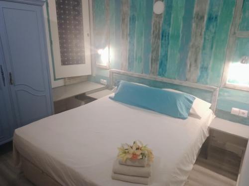 阿尔么丽亚Casa Violette的卧室配有白色床、蓝色枕头和毛巾