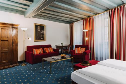雷根斯堡Altstadthotel Arch的酒店客房,配有一张床和两张红色椅子
