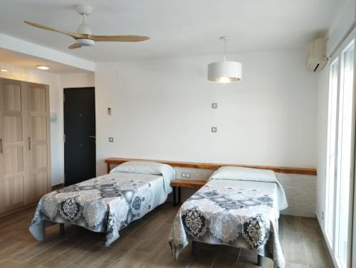德尼亚Casa Samsara Yaranda的客房设有两张床和吊扇。