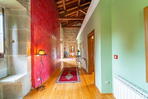 AmoeiroCasa Rural Pazo San Damian的带有红色墙壁的建筑走廊