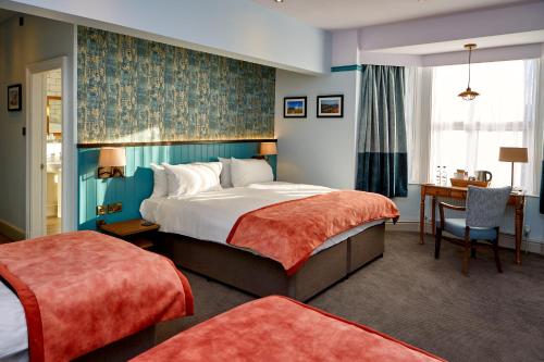 梅奈布里奇安格尔西纹章酒店的酒店客房设有一张大床和一张书桌。