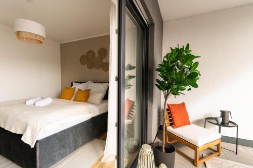 巴特赫尔斯费尔德DWELLSTAY - Modernes Apartment I 55qm I 2 Zimmer I Küche I Bad I Terrasse I TV I Netflix的一间卧室配有床、椅子和植物