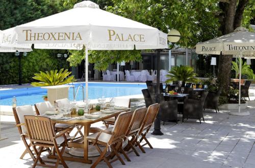 雅典迪奥森尼亚宫酒店的游泳池旁配有桌椅和遮阳伞