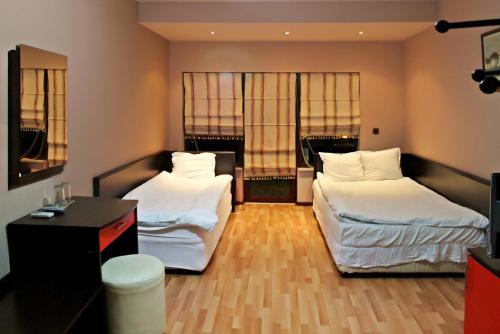 莫姆奇尔格勒Hotel Berito的客房设有两张床、一张书桌和两个窗户。