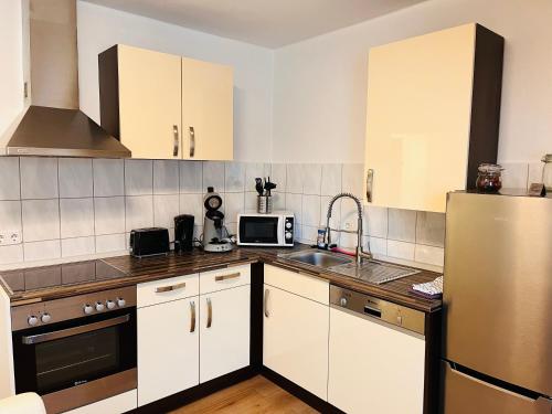 格拉德贝克Ferienwohnung Götel的厨房配有白色橱柜和不锈钢冰箱