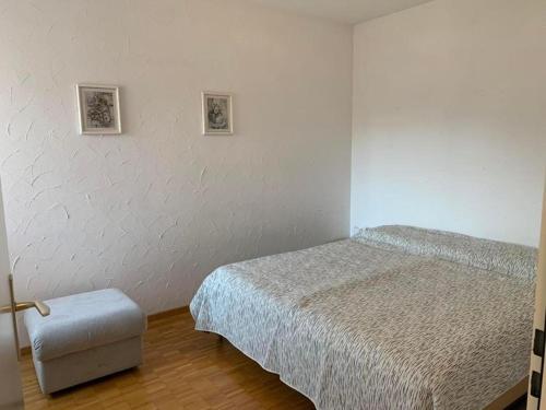 卡斯拉诺Sonnige 35 Zi-Ferienwohnung in Caslano的一间卧室配有一张床和一张凳子,墙上有两张照片