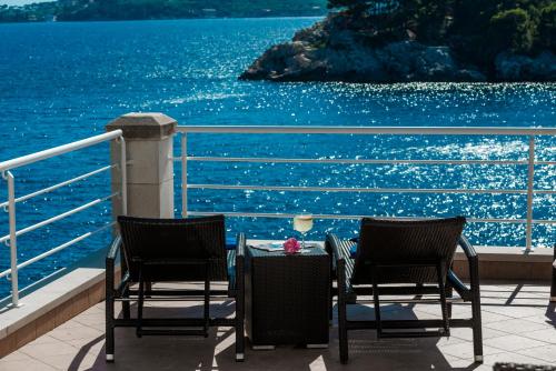 杜布罗夫尼克Villa Vacanza Dubrovnik - Five Bedroom Villa with Private Sea Access的俯瞰水面的阳台配有两把椅子和一张桌子