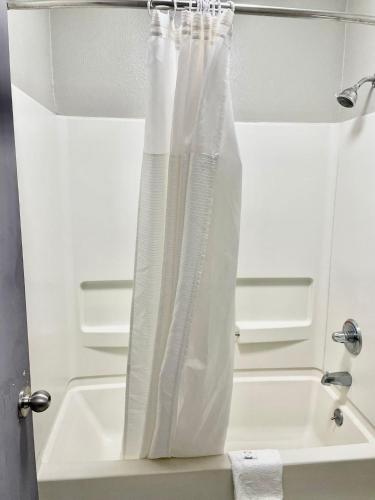孟菲斯American Way Inn & Suites的浴室设有淋浴帘,位于水槽旁