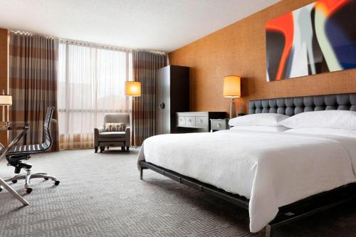 夏洛特夏洛特喜来登酒店的酒店客房带一张大床和一把椅子