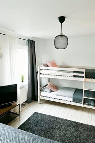 策勒Modernes Apartment mit Balkon free Parking Netflix的卧室配有白色双层床和电视。