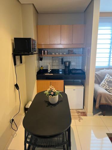 圣保罗Flat super equipado的一间小厨房,内设一张带鲜花的黑色桌子