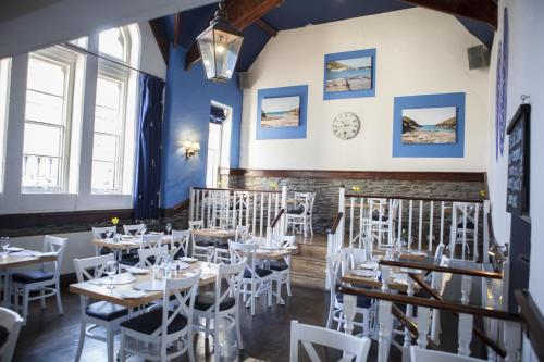 以撒港复古学院酒店的用餐室配有桌子和白色椅子