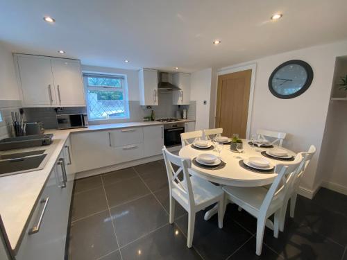 兰鲁斯特Modern 4-bed Cottage Llanwrst Town Centre & Parking - Snowdonia! near Betws-y-Coed的厨房配有桌椅和墙上的时钟