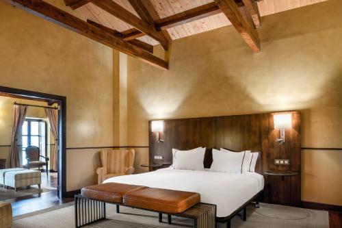 圣地亚哥－德孔波斯特拉卡门宫傲途格精选酒店的一间卧室配有一张大床和一把椅子