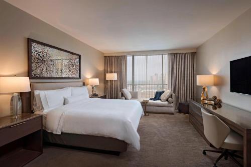 休斯顿The Westin Galleria Houston的酒店客房配有一张床、一张书桌和一台电视。